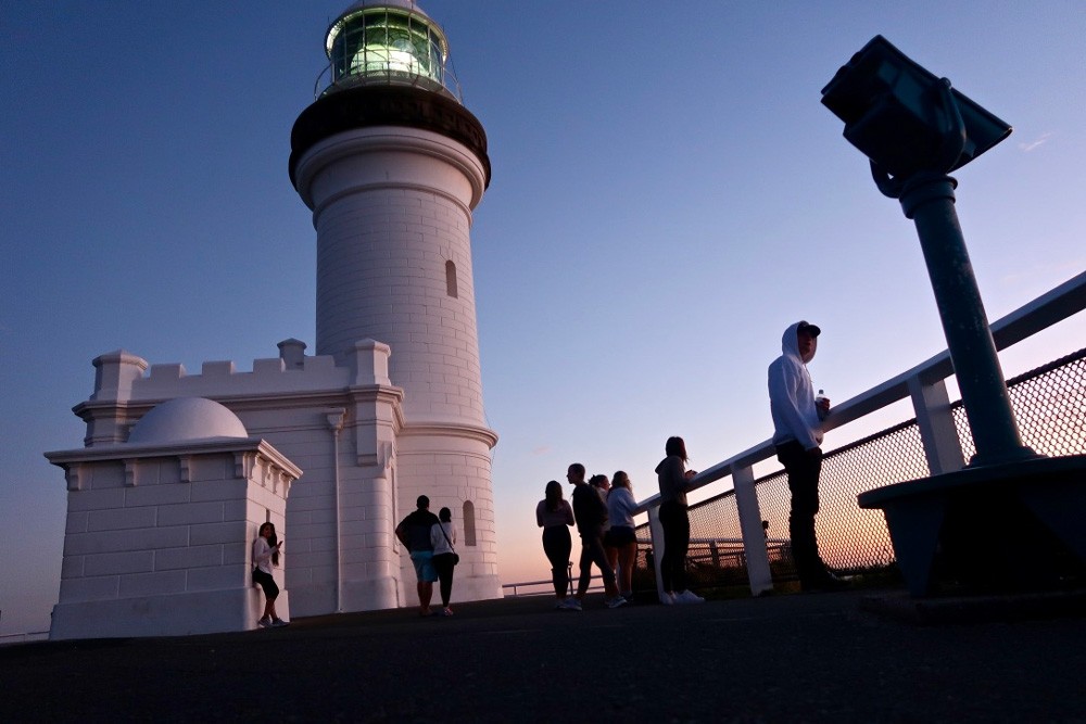 Fotografía de la puesta del Sol en el faro de Byron Bay en Australia con gente 